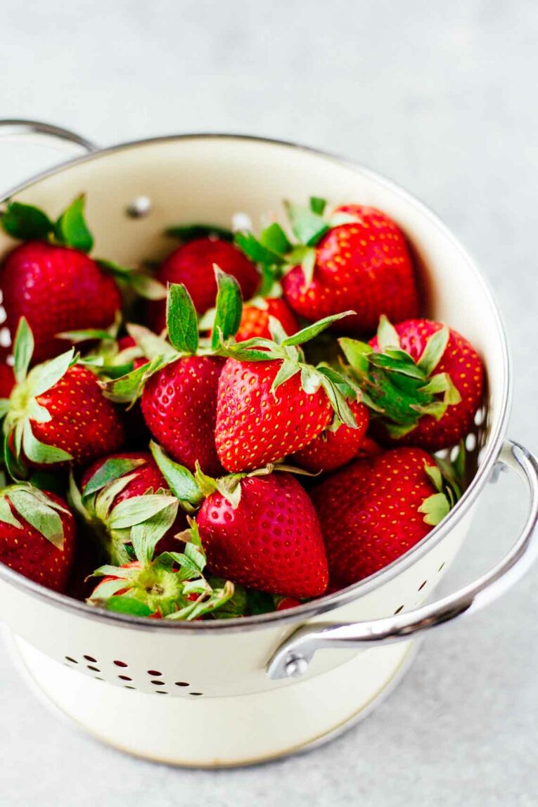 white colander full of strawberries
