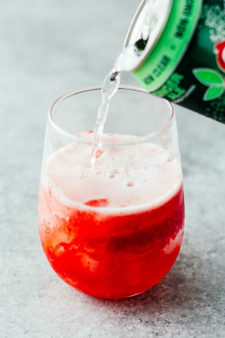 ginger ale being poured into a glass with strawberries