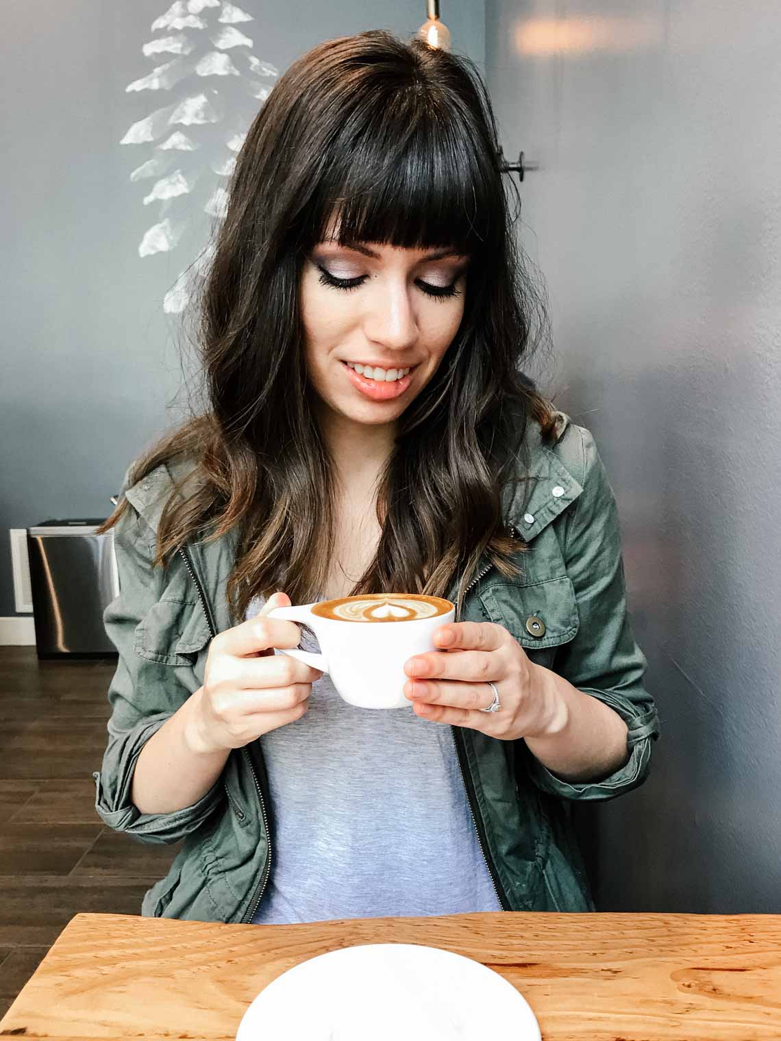 Girl holding latte inside Three Pines Coffee shop in Salt Lake City