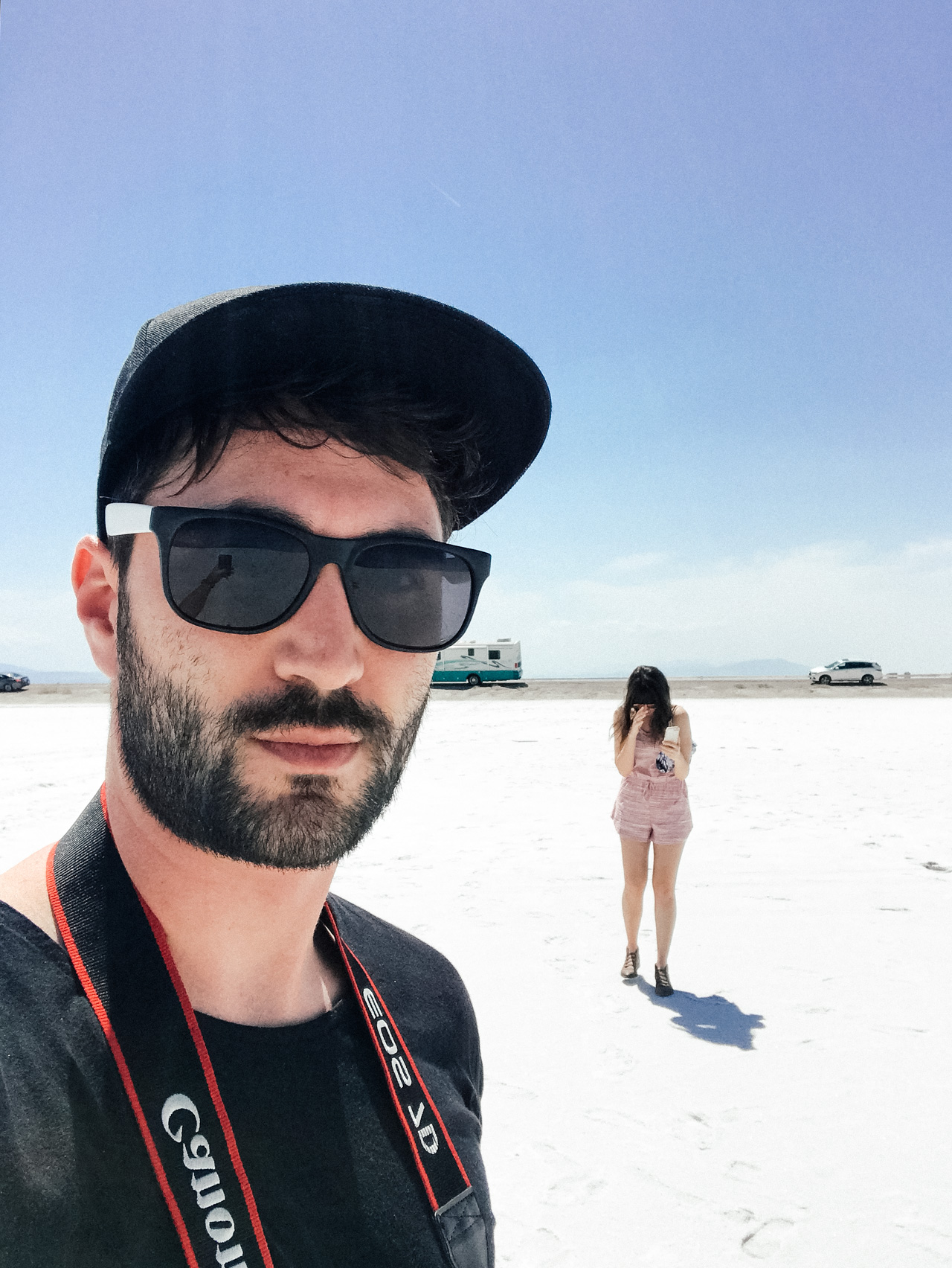 Guy taking selfie outside with girl in the background