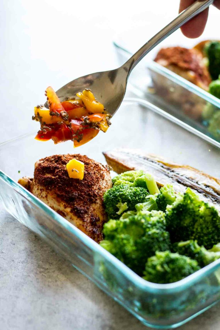 Adding mango salsa to meal prep bowls