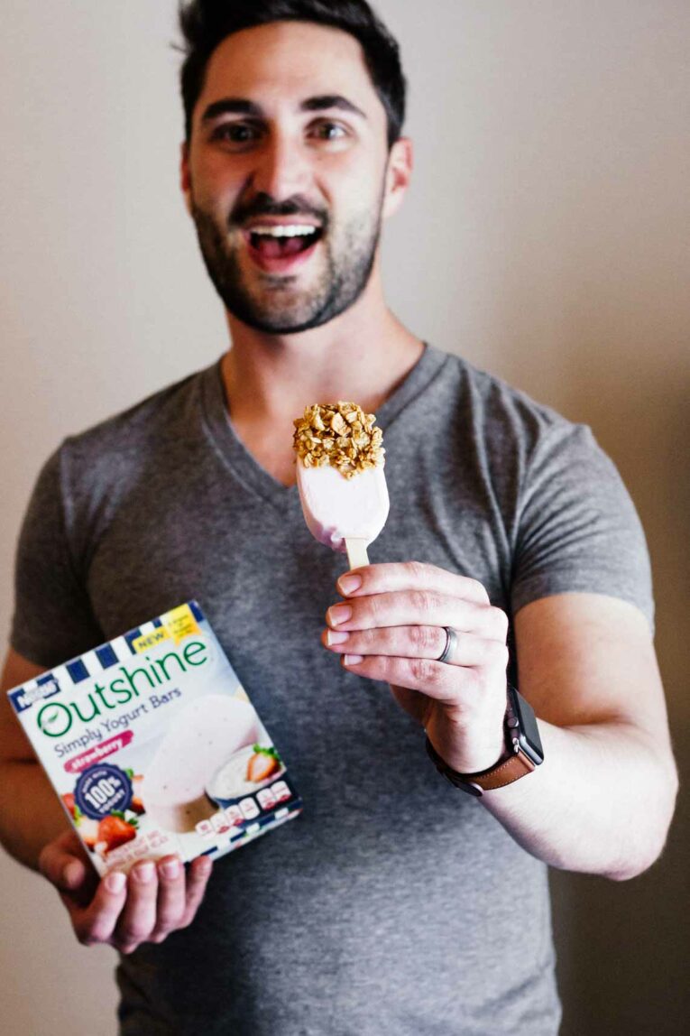 A man holding a strawberry frozen yogurt bar 