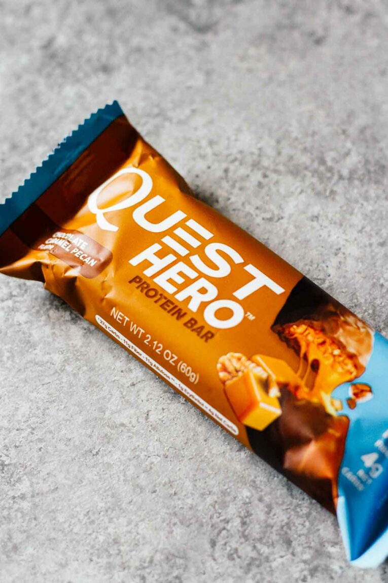 Chocolate Caramel Pecan Yogurt Bowls for an easy and delicious breakfast! Loaded with protein and great for taking on-the-go! #yogurtbowls #breakfastbowls #pecans Quest Hero Protein Bar Chocolate Caramel Pecan on a gray surface