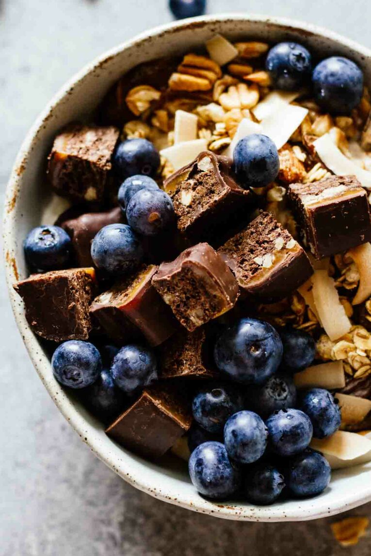 Chocolate Caramel Pecan Yogurt Bowls for an easy and delicious breakfast! Loaded with protein and great for taking on-the-go! #yogurtbowls #breakfastbowls #pecans A close up of a Loaded yogurt bowl with Chocolate Caramel Pecan Quest Hero Protein Bar