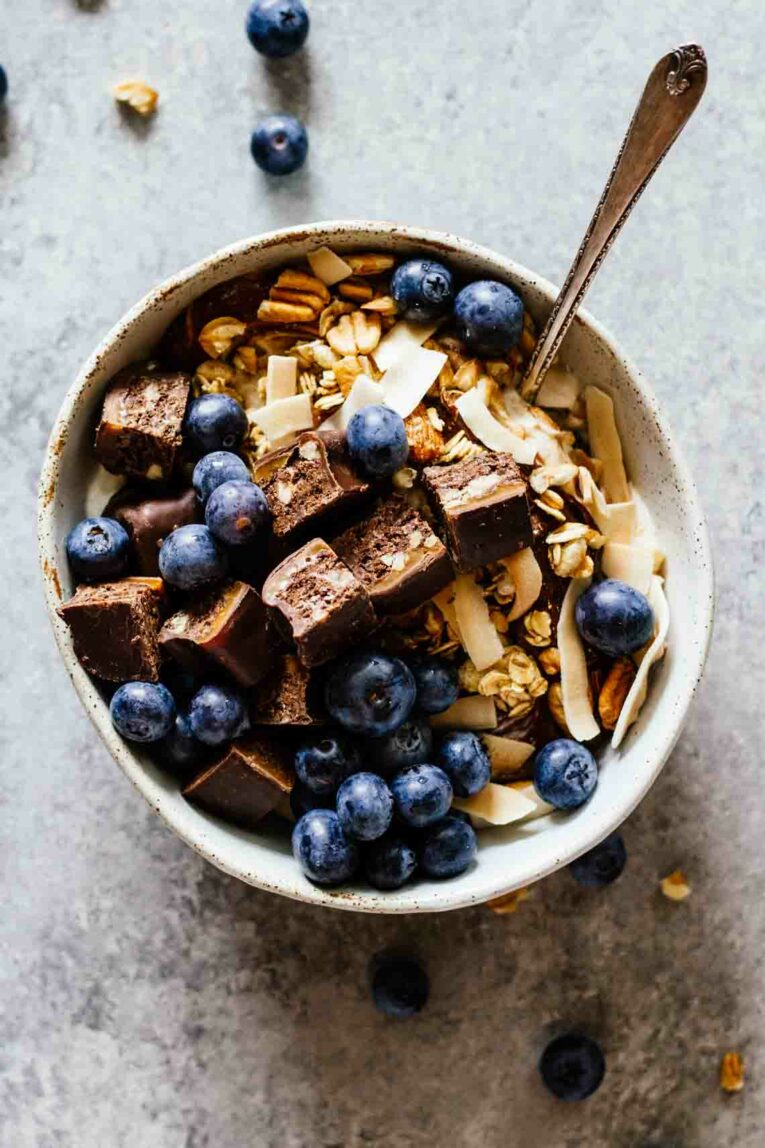 Chocolate Caramel Pecan Yogurt Bowls for an easy and delicious breakfast! Loaded with protein and great for taking on-the-go! #yogurtbowls #breakfastbowls #pecans An overhead shot of a Chocolate Caramel Pecan Yogurt Bowl with a spoon