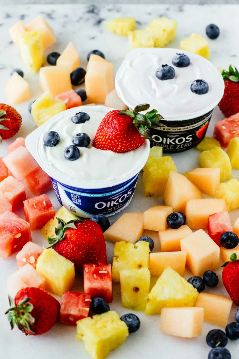2 cups of yogurt surrounded by berries on a counter