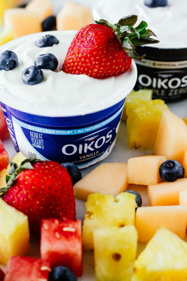Close up shot of yogurt in a cup surrounded by fruit