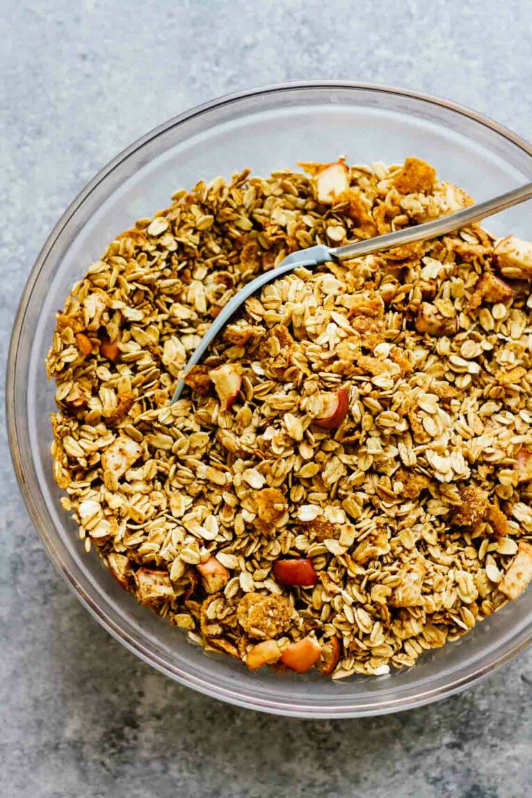 Overhead shot of Maple Apple Spice Gluten Free Granola in a glass bowl with a spoon