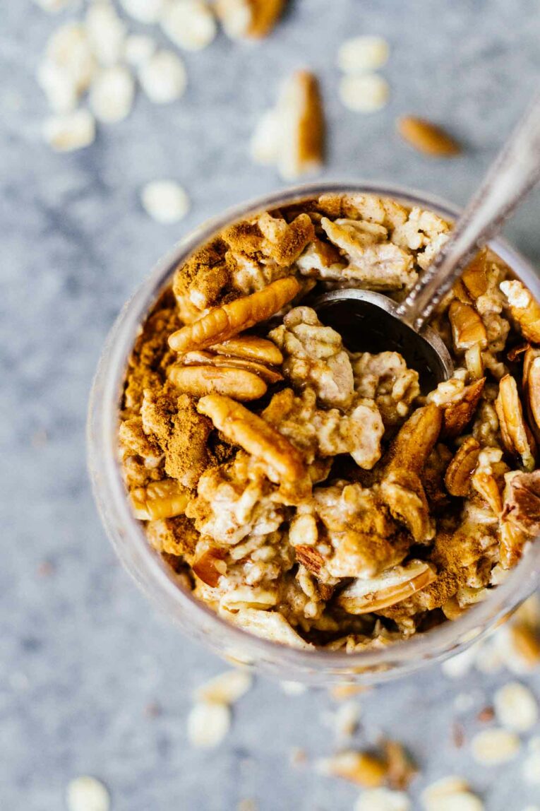 Overhead shot of Maple Cinnamon Pecan Overnight Oats in a glass with a spoon