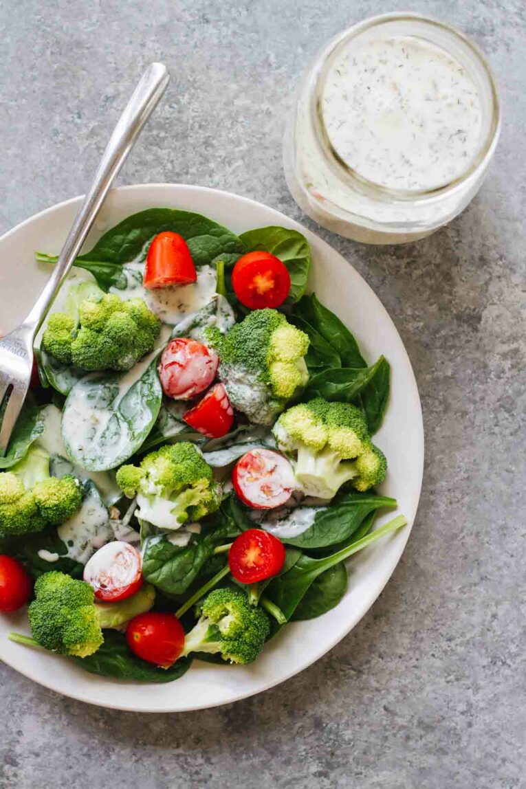 A salad served on a white plate with a fork next to Kefir 10-Minute Healthy Ranch Dressing in a mason jar.
