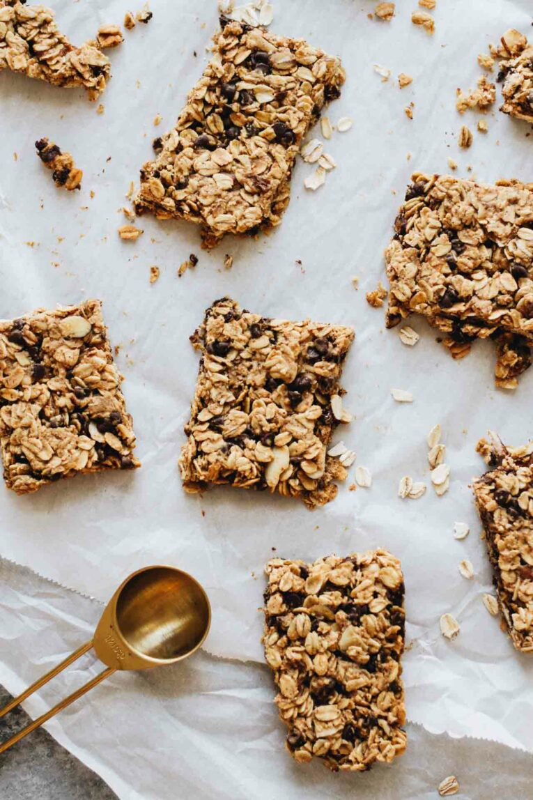 Oatmeal breakfast bars on parchment paper with rolled oats.