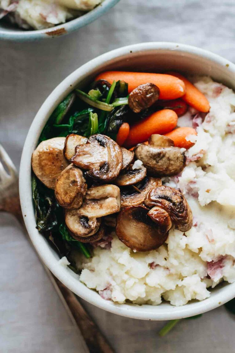 Vegan mashed potatoes topped with sautéed carrots, mushrooms, and spinach.