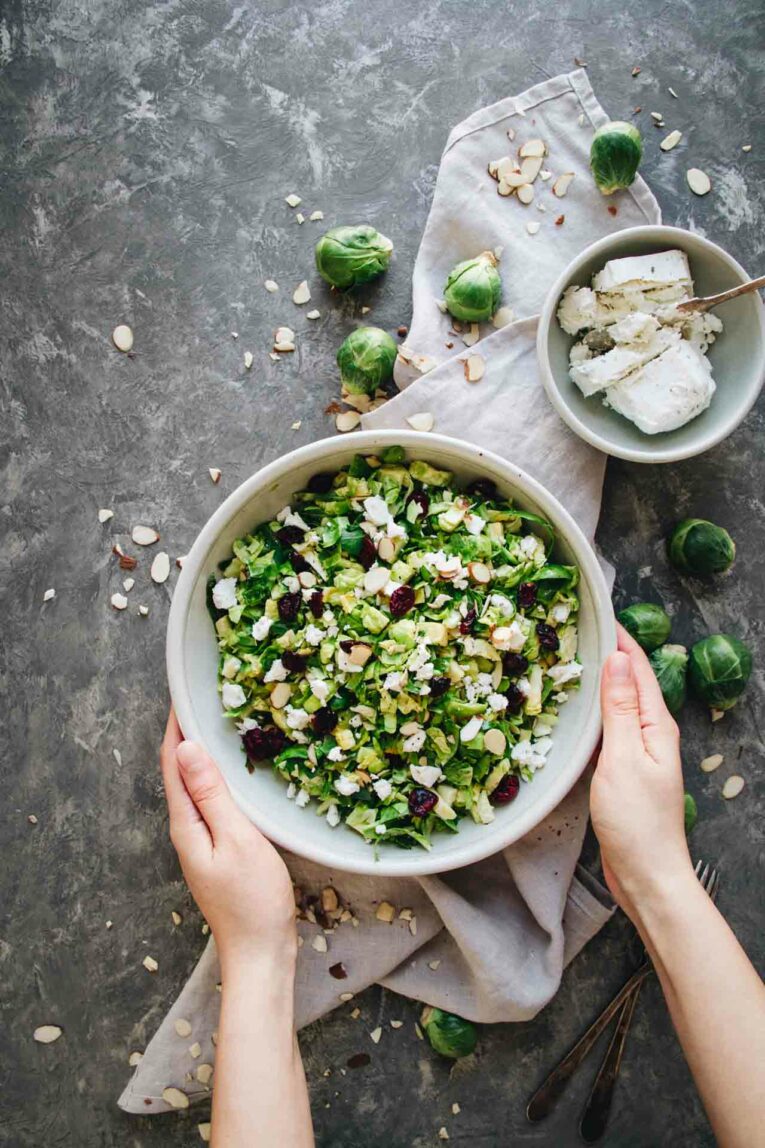 hand holding bowl of Shaved Brussels Sprout Salad w/ Cranberries! 