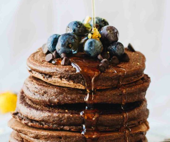 Chocolate Protein Pancakes with blueberries and syrup pouring over them! Loaded with superfoods, protein, fruit, eggs, and rolled oats. They also happen to be gluten and dairy free!