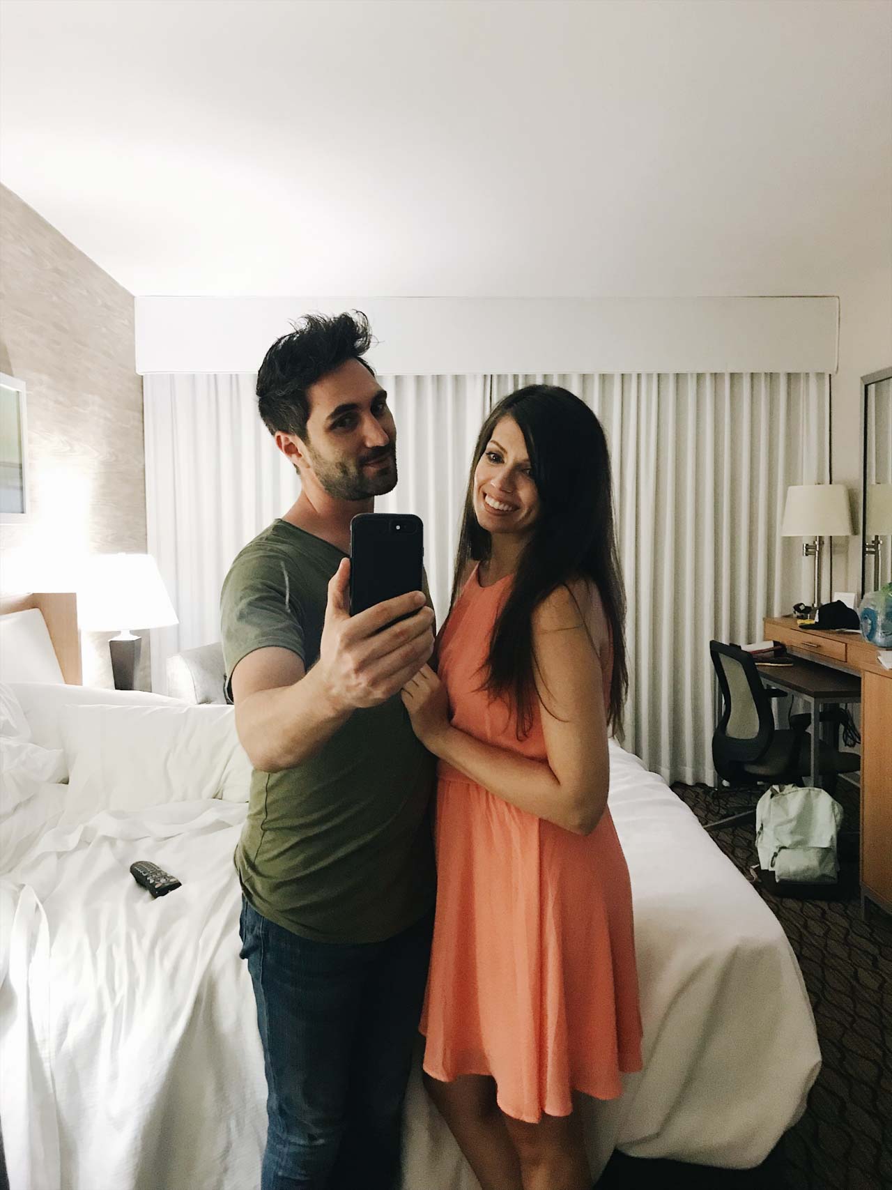 Couple standing in hotel room taking a selfie