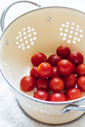 Grape tomatoes in a white colander.