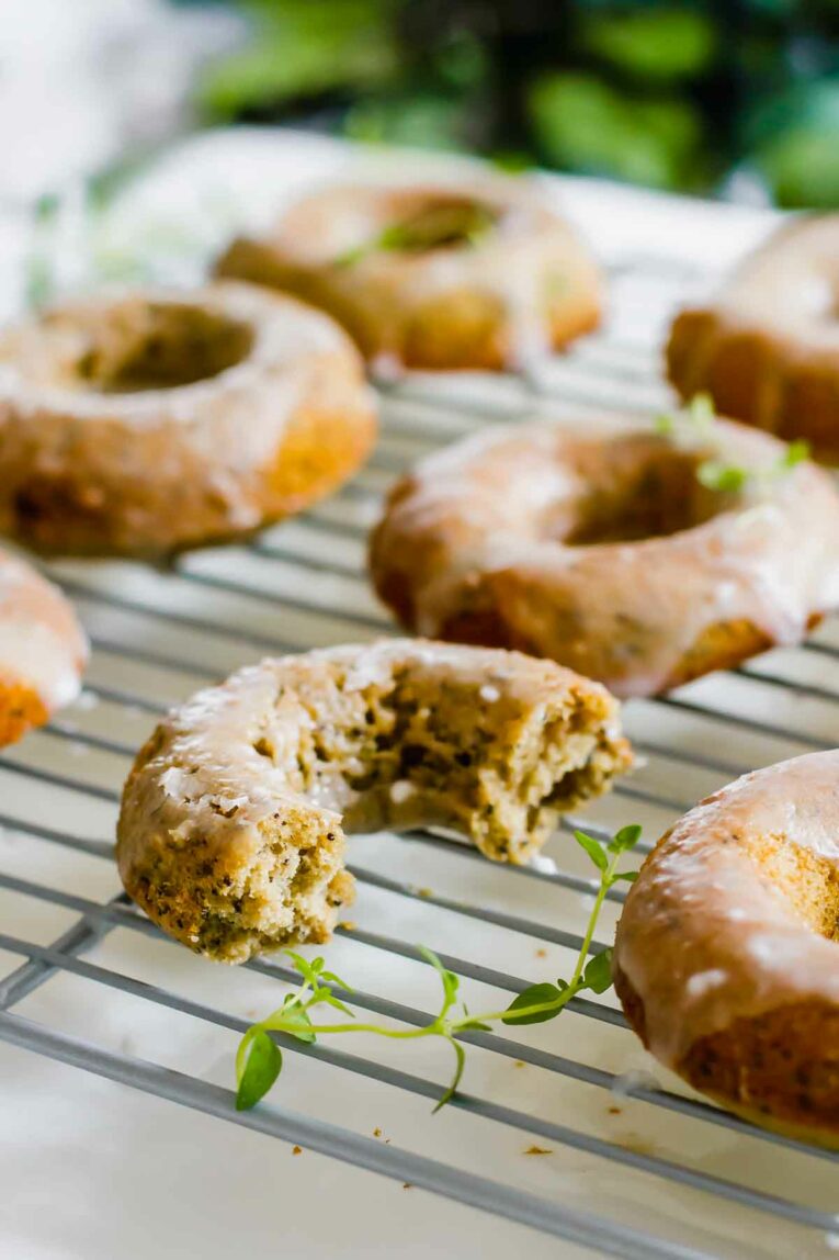 Delicious Lemon Poppyseed Healthy Baked Donuts with a bite taken out sitting on a cooling rack!
