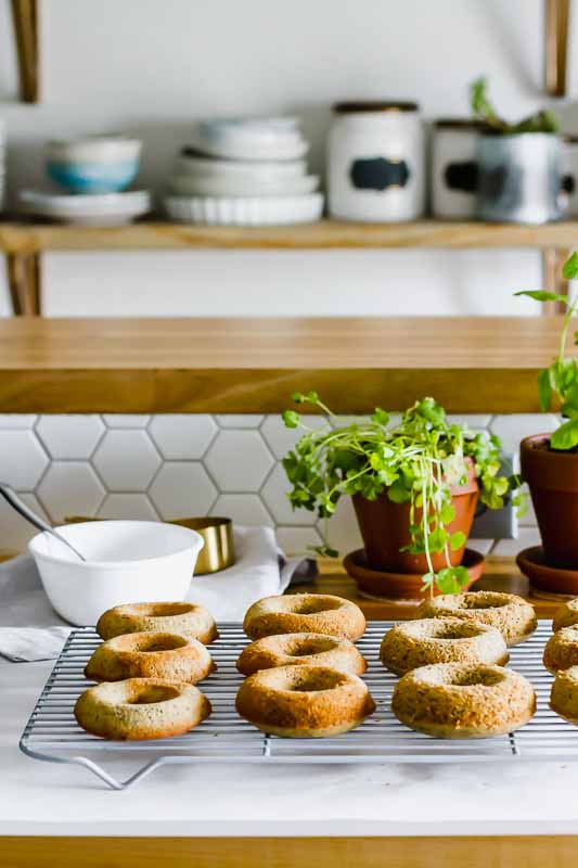 lemon poppyseed donuts on a cooling rack with kitchen in the background.
