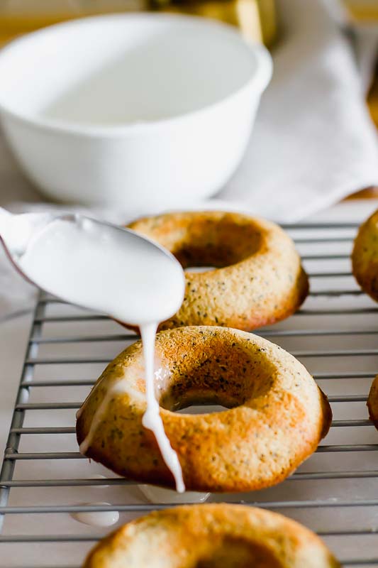 Sugar glaze drizzled on a lemon poppyseed healthy baked donuts on a cooling rack.