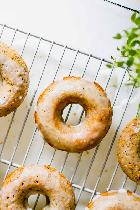 Overhead shot of Sweet, fluffy Lemon Poppyseed Healthy Baked Donuts drizzled with a melt-in-your-mouth glaze  on a cooling rack.