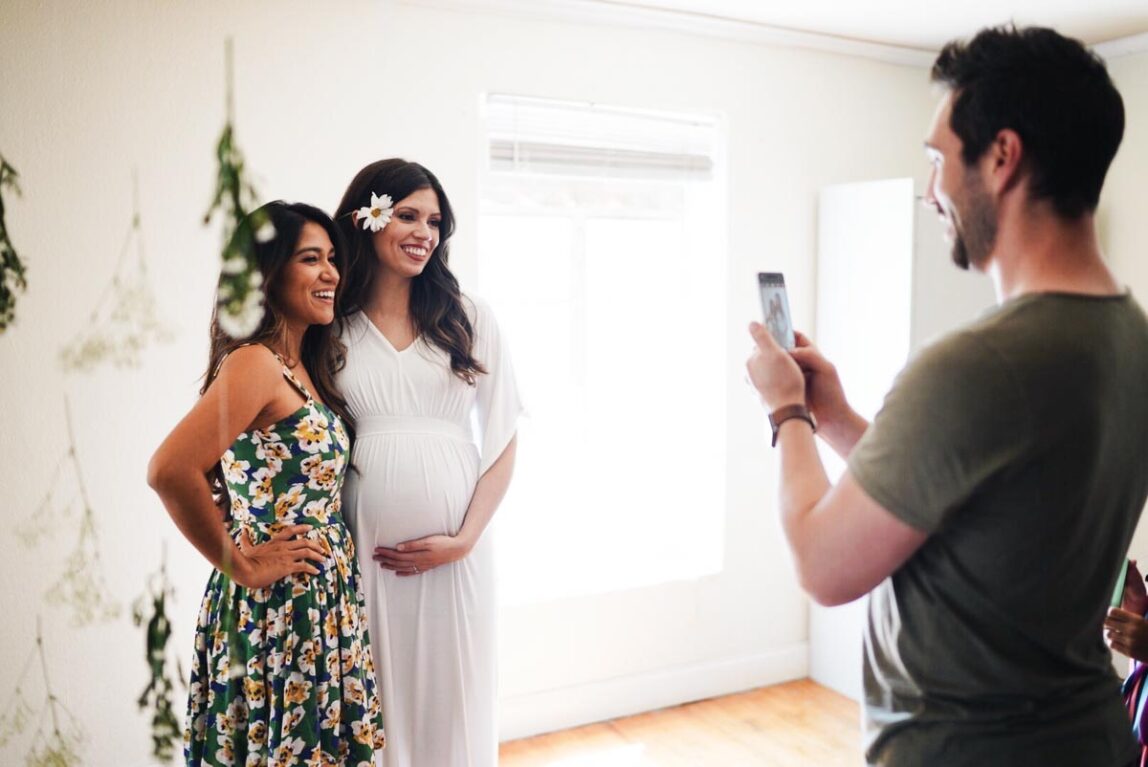 Two girls getting their photo taken by a guy.