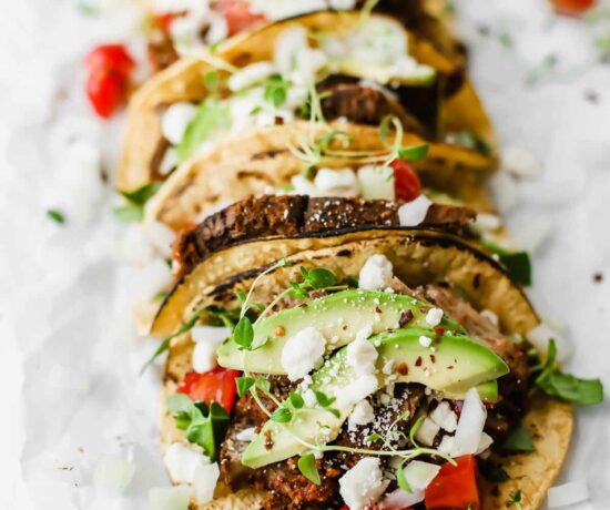 Easy Mexican Barbacoa Tacos by Jar Of Lemons! Corn tortillas topped with slow cooked chuck roast beef, avocado, tomatoes, onions, and feta cheese. So yummy!