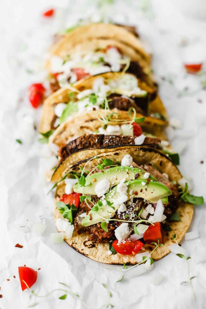 Easy Mexican Barbacoa Tacos by Jar Of Lemons! Corn tortillas topped with slow cooked chuck roast beef, avocado, tomatoes, onions, and feta cheese. So yummy!