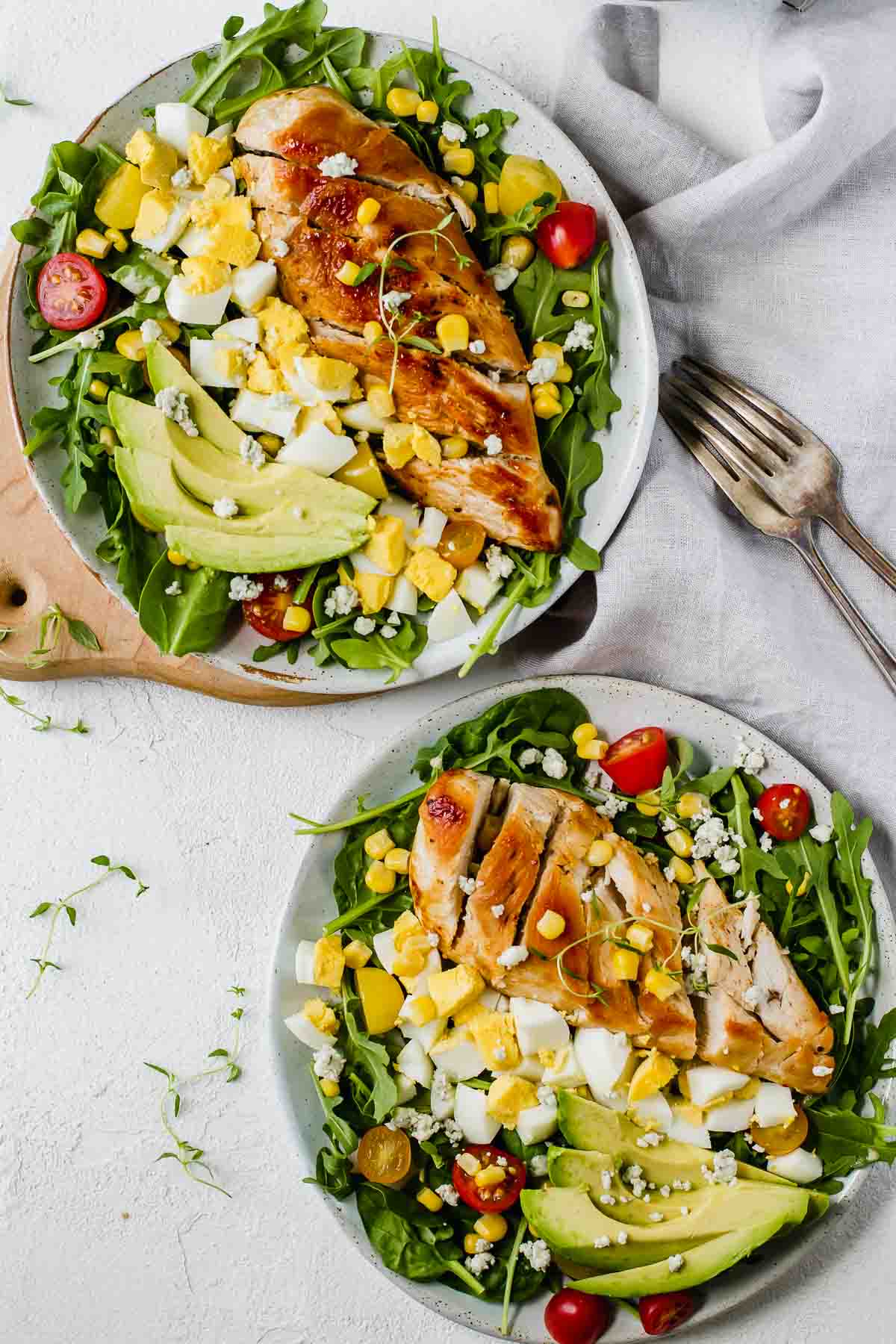 Healthy Chicken Cobb Salad Recipe loaded with spicy greens, creamy avocado, boiled eggs, fresh tomatoes, corn, delicious grilled chicken, and topped with a sprinkle of blue cheese crumbles. So yummy! (Gluten Free)