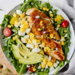 Healthy Chicken Cobb Salad Recipe loaded with spicy greens, creamy avocado, boiled eggs, fresh tomatoes, corn, delicious grilled chicken, and topped with a sprinkle of blue cheese crumbles. So yummy! (Gluten Free)