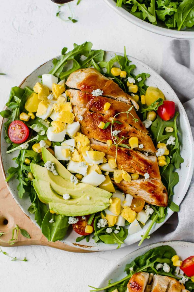 Healthy Chicken Cobb Salad Recipe loaded with spicy greens, creamy avocado, boiled eggs, fresh tomatoes, corn, delicious grilled chicken, and topped with a sprinkle of blue cheese crumbles. So yummy! (Gluten Free)
