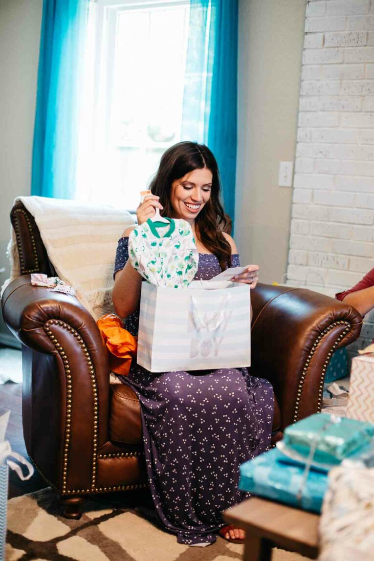 girl opening baby shower gifts.