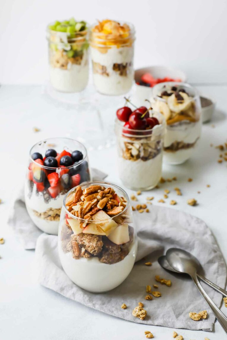 Protein-Loaded Yogurt Parfait Recipes with yogurt, granola, and fruit in glass jars arranged on a white counter.