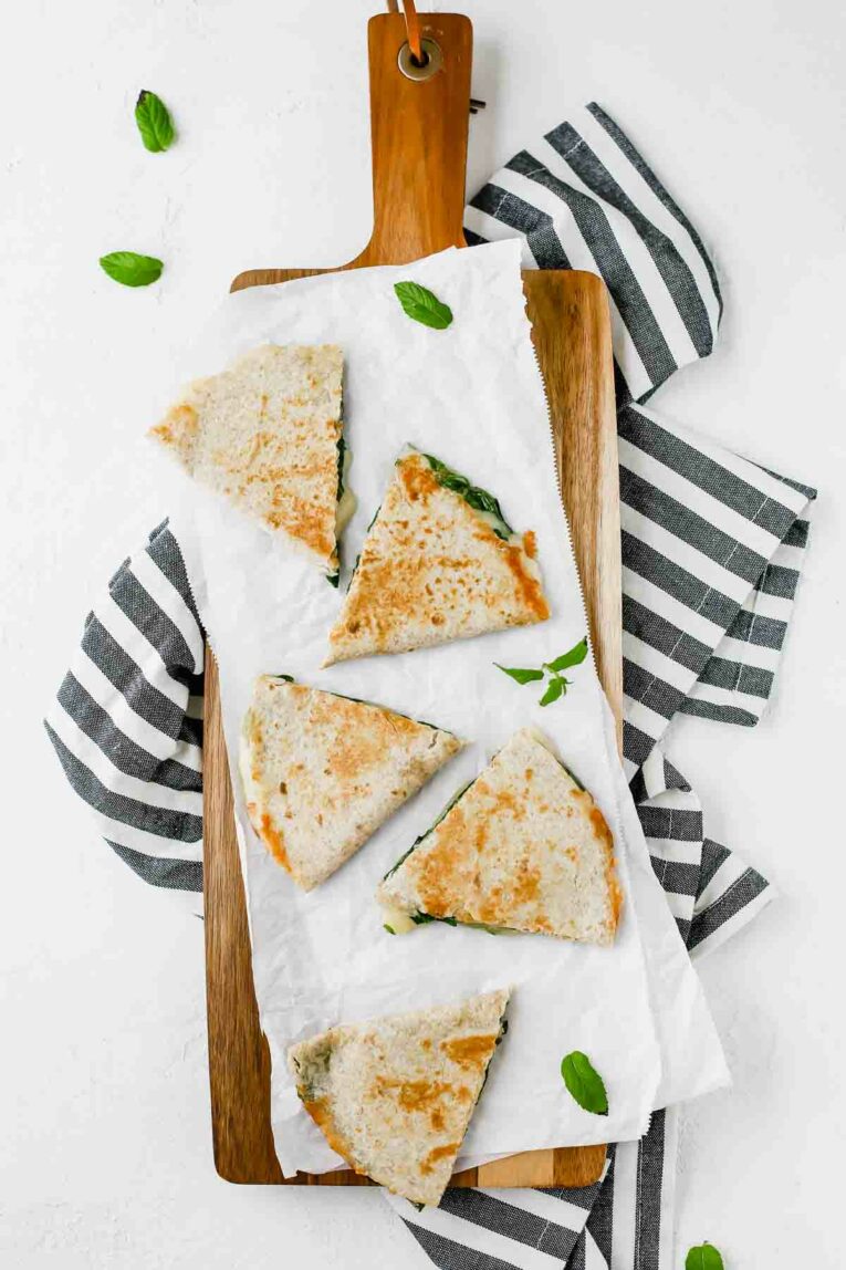 5-Minute Spinach Vegetarian Quesadillas on a cutting board sitting on a striped dish towel.