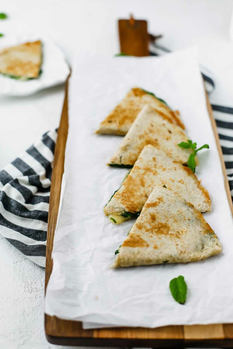 Side view of 5-Minute Spinach Vegetarian Quesadillas in a line on a cutting board.