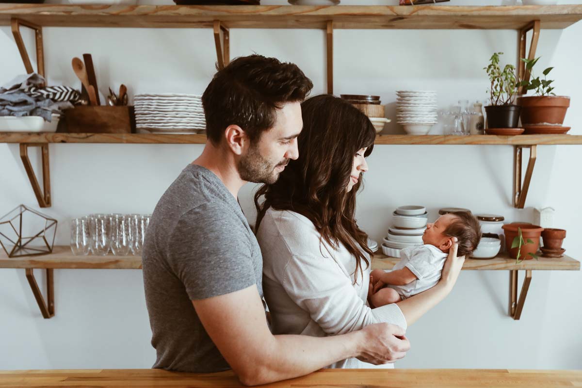 Couple holding a looking at their newborn baby.