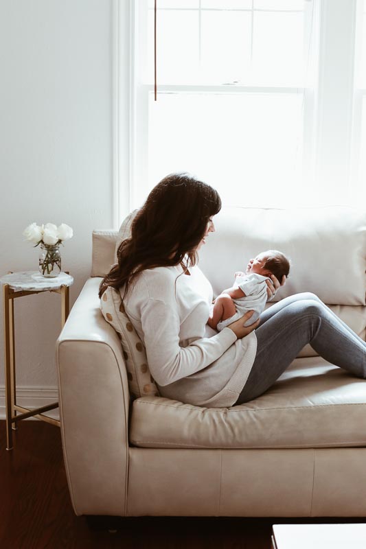 mom sitting on the couch holding newborn baby.