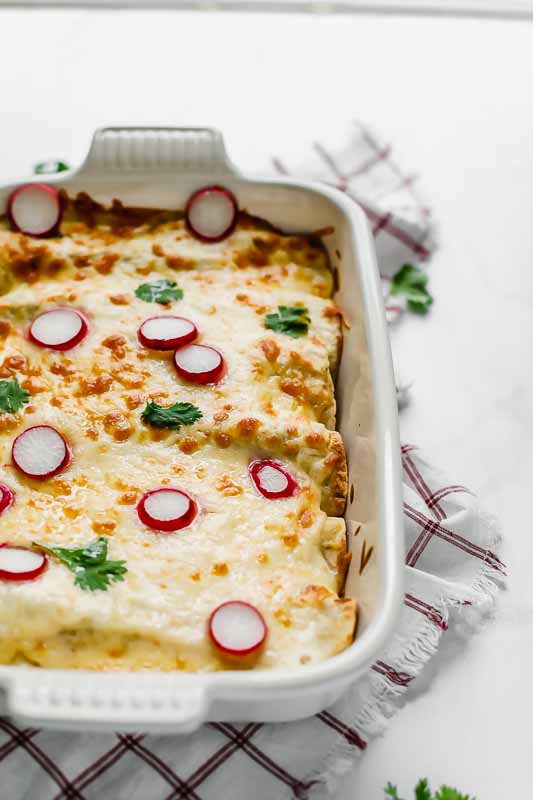 Skinny Creamy Chicken Enchiladas in a white baking dish.