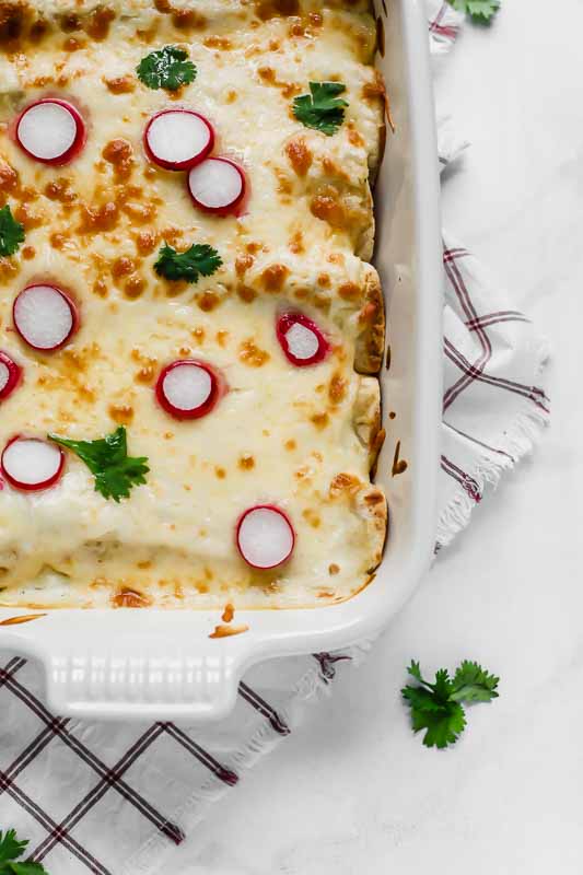 Skinny Creamy Chicken Enchiladas in a white baking dish.