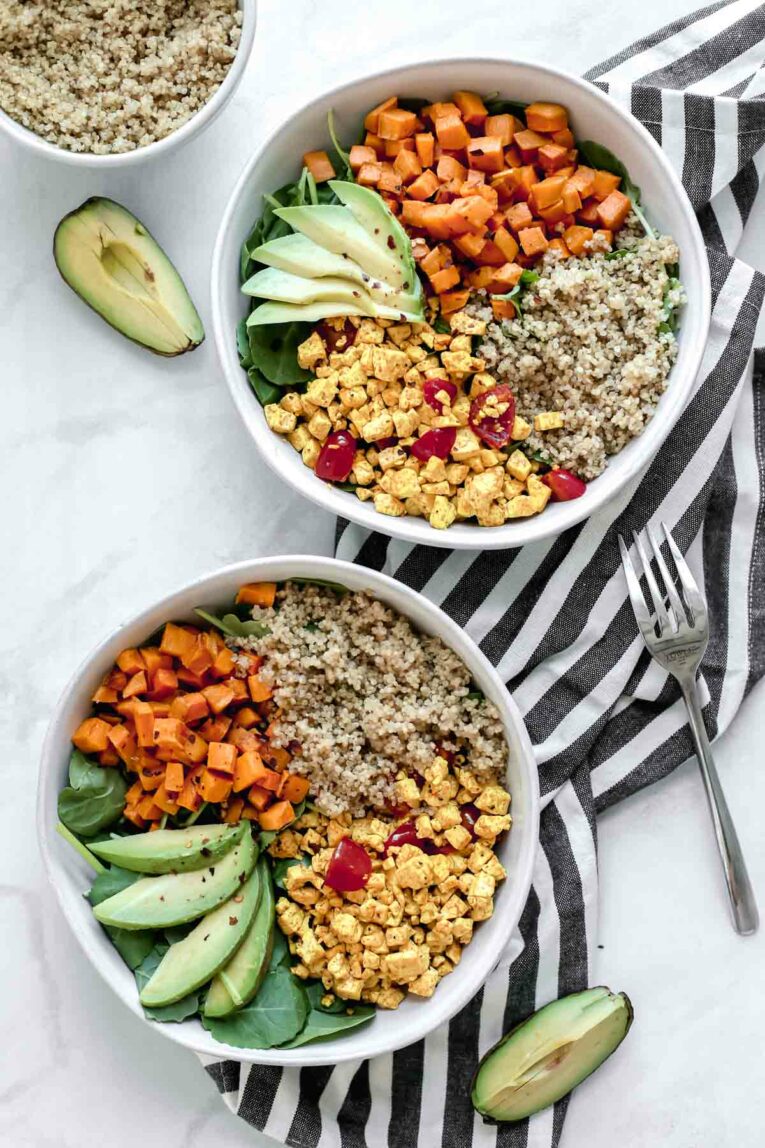 Overhead shot of two Tofu Scramble Vegan Breakfast Bowls served in two white bowls on a striped dishcloth.