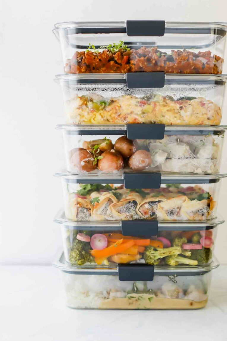 6 Healthy Freezer Meals For New Moms stacked on top of each other in glass meal prep containers.
