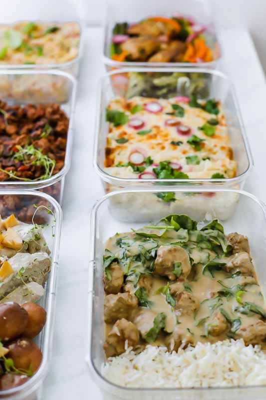 6 Healthy Freezer Meals For New Moms in food prep containers on a countertop.