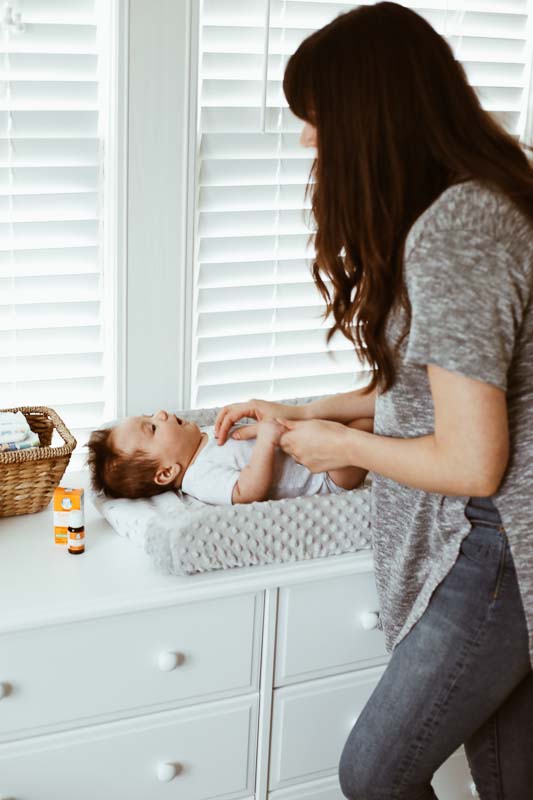 baby laying on changing pad with mom looking at him.