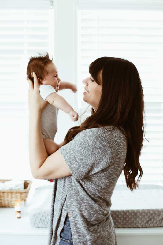 Mom holding baby close to face while smiling.