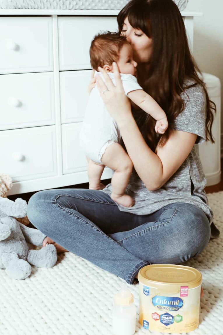 Mom holding baby up to her face to kiss him. 