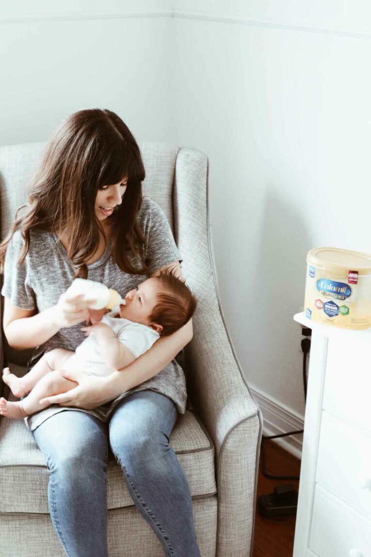 Mom sitting in rocker, holding a baby and giving him a bottle.