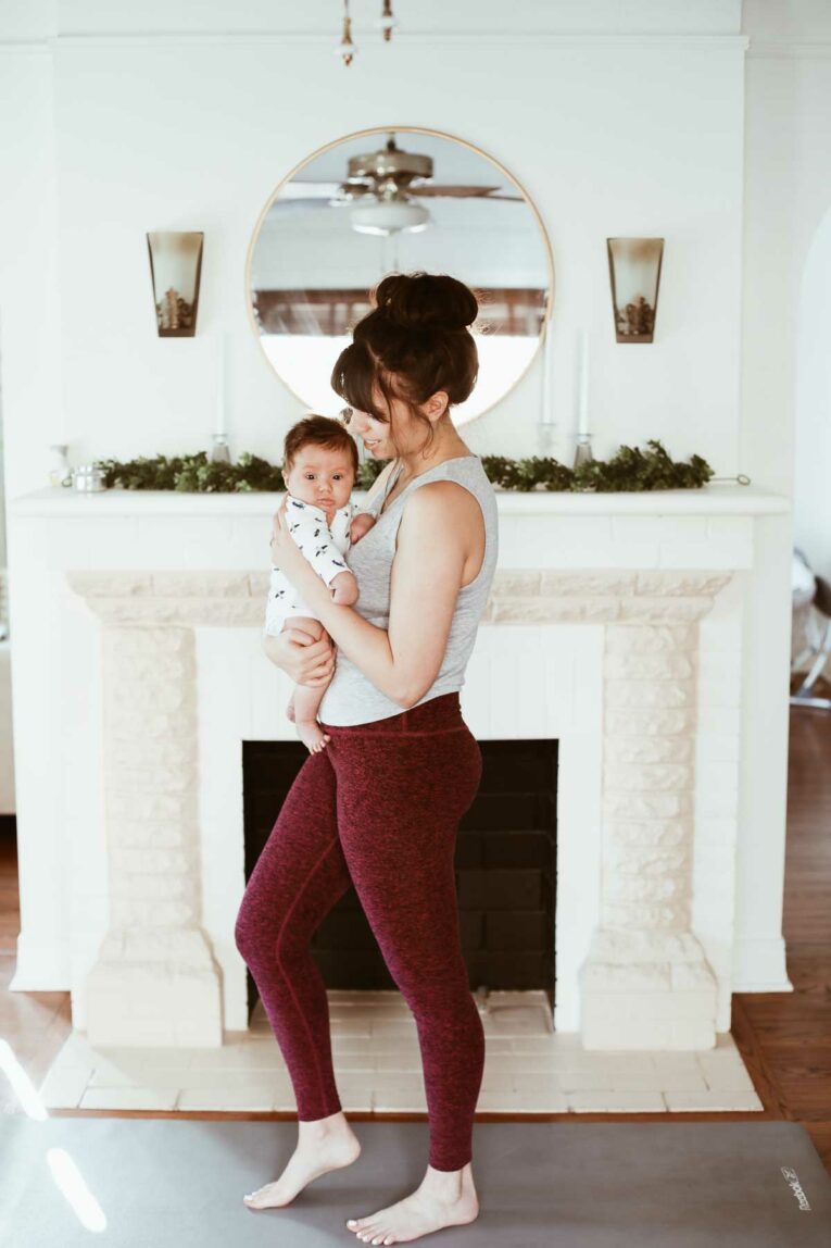 mom in workout gear holding baby close to her.