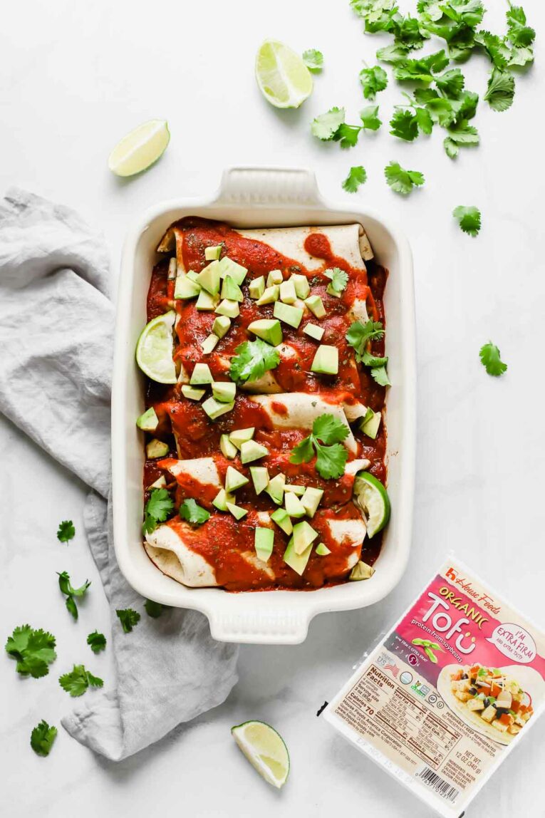 Overhead shot of 5-Ingredient Vegan Enchiladas in a white baking dish on a light grey dishcloth.