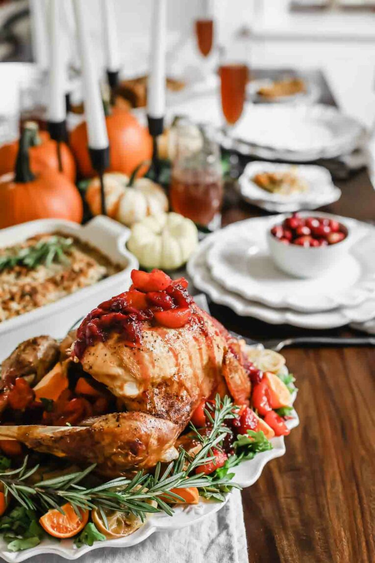 The BEST Citrus Tea-Glazed Roasted Turkey sitting on a table set for Thanksgiving.