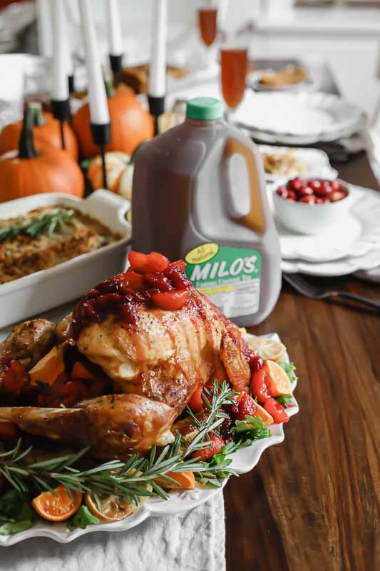 The BEST Citrus Tea-Glazed Roasted Turkey sitting on a thanksgiving table next to Milo's tea.