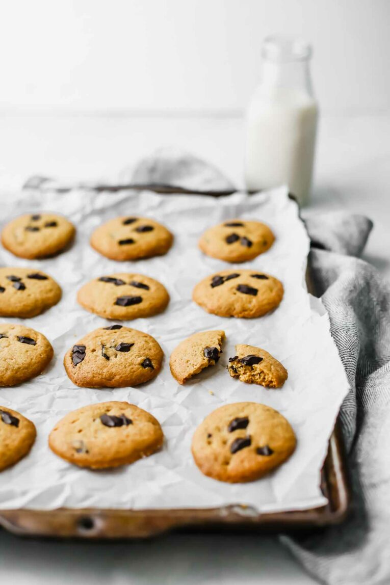 Side angle of The BEST Chocolate Chip Healthy Cookie Recipe on a cookie sheet with a glass of milk in the background.